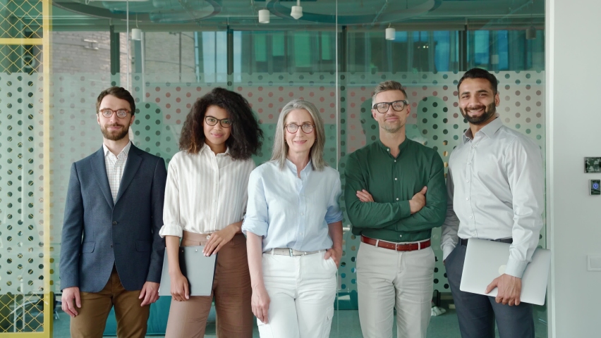 Happy diverse business people team standing together in office, group portrait. Smiling multiethnic international young professional employees company staff with older executive leader look at camera. | Shutterstock HD Video #1076059670