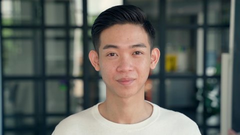 Portrait of young cheerful happy smiling asian chinese high school college university student, IT startup worker standing in contemporary office background looking at camera. Headshot. Close up.