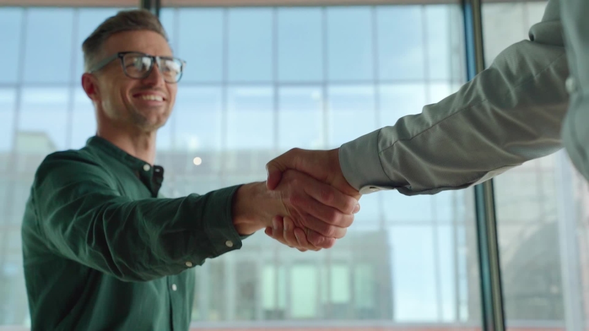 Two happy diverse professional business men executive leaders shaking hands at office meeting. Smiling businessman standing greeting partner with handshake. Leadership, trust, partnership concept. Royalty-Free Stock Footage #1076061551