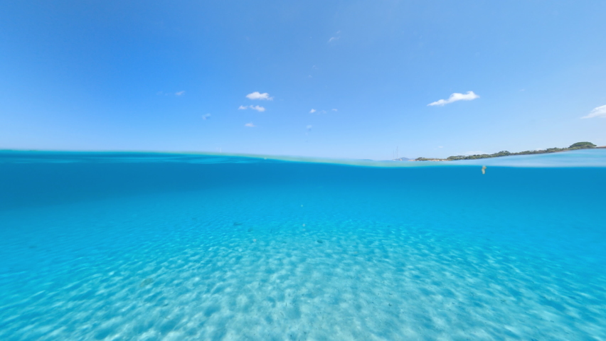 Split-shot, over-under shot. Stunning view of half underwater half sky with a beautiful and turquoise water. Romazzino beach, Costa Smeralda, Sardinia, Italy. Royalty-Free Stock Footage #1076065601