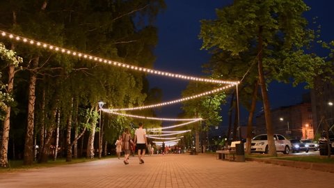
Editorial use only;  View of the city at night, people walk the footpaths at night in summer, the street is illuminated with garlands,  Chelyabinsk, Russia - May 17, 2021