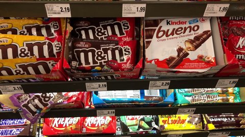 Alameda, CA - July 15, 2021: 4K HD video panning down candy bars in a display at check out line in grocery store, placed in a highly visible place where you will see it to potentiate impulse purchases