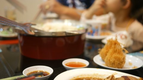 Family enjoys eating Sukiyaki , Japanese style food on table