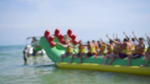 A group of people ride an inflatable boat, an attraction on the water. Blurred background, concept of summer vacation on the beach.