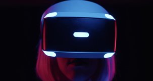 Close up stylish female future gamer wearing virtual reality headset in black background. Cyberpunk woman play virtual reality online gaming using modern 3D VR glasses and makes hand gestures