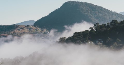 Time Lapse. Aerial view of Itaipava, Petrópolis. Early morning with a lot of fog in the city. Mountains with blue sky and clouds around Petrópolis, mountainous region of Rio de Janeiro, Brazil.