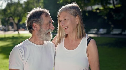 Elderly Man And Woman In Park After Fitness Talk And Have Fun. They Smile. Gray Haired Man With Beard And Woman With Long Hair.