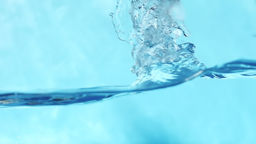 Slow motion video of water waves with splashes and falling drops on a blue background. Royalty-Free Stock Footage #1076090966