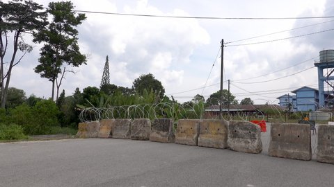 KUANTAN, PAHANG, MALAYSIA - JULY, 18th 2021 : The authorities have placed concrete traffic barriers and barb wires at the entrance area infected with the covid-19 outbreak.