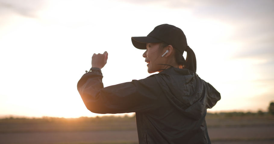 Sport Asian Girl listening to music and dancing with smiling at the beautiful sunset. 4k Slow motion.