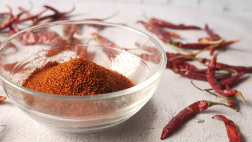 Chili powder and dried peppers on table background.
