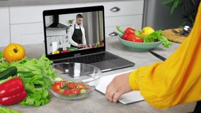 Housewife in kitchen knives sliced tomato from cutting board into salad bowl, study online cooking lesson. Man chef food blogger in laptop screen slices tomato tells teaches woman video call computer