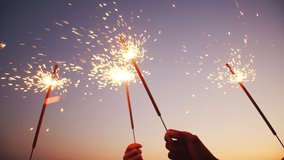 Closeup of hands holding sparklers, happy friends are waving bengal fireworks against background of evening sky. Concept of party - Powered by Shutterstock - Get 15% off with code: PIKWIZARD15