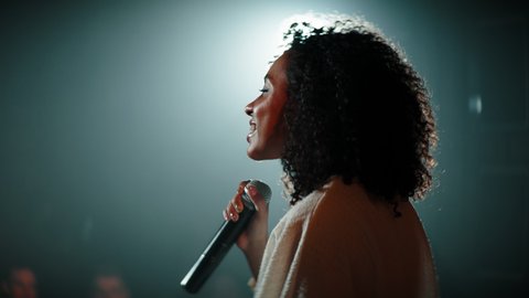 CU HANDHELD Portrait of Black African American young female comedian finishing her stand-up monologue and leaving stage of a small venue. Shot with ARRI Alexa Mini LF with 2x anamorphic lens