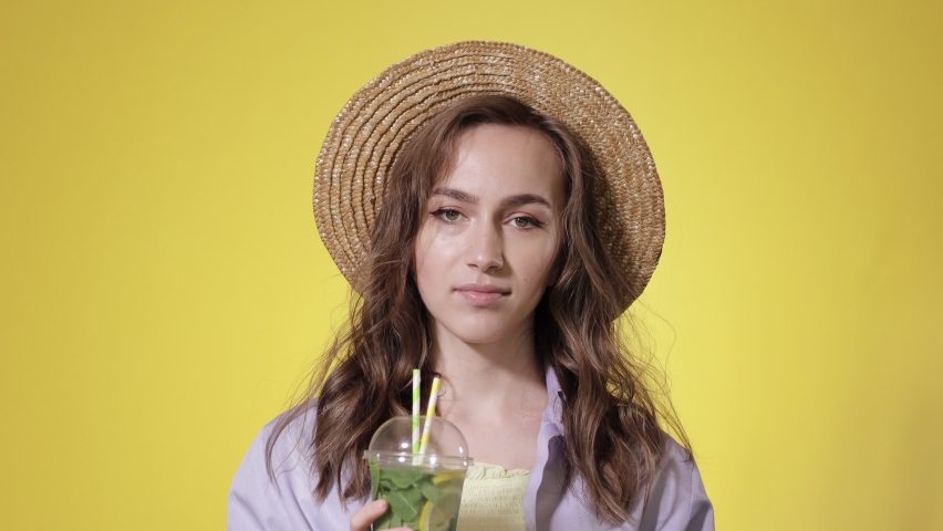 Surprised Woman Drink Mojito cocktail From Plastic Cup Over Yellow Studio Background. Summer refreshment. Cold beverage Royalty-Free Stock Footage #1076104202