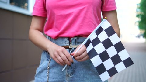 Woman holding and waving Checkered race flag at the street