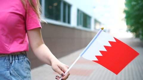 Unrecognizable woman holding Bahraini flag. Girl walking down street with national flag of Bahrain