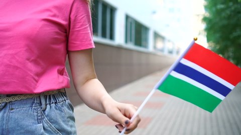 Unrecognizable woman holding Gambian flag. Girl walking down street with national flag of Gambia
