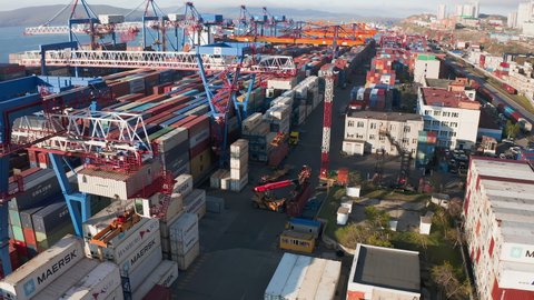 Vladivostok, Russia - May 11, 2021: Aerial drone footage of a cargo terminal with ships.The terminal operates gantry cranes. The containers are stacked. Railway wagons with coal