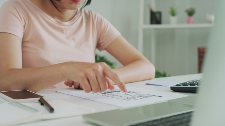 A woman checks documents and scans to pay the invoice. A woman is using a phone scan to verify the details according to the documents. woman paying online. Royalty-Free Stock Footage #1076108483