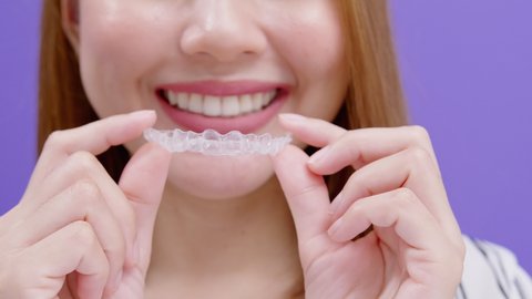 Young smiling woman holding Invisalign braces in studio, dental healthcare and Orthodontic concept.	