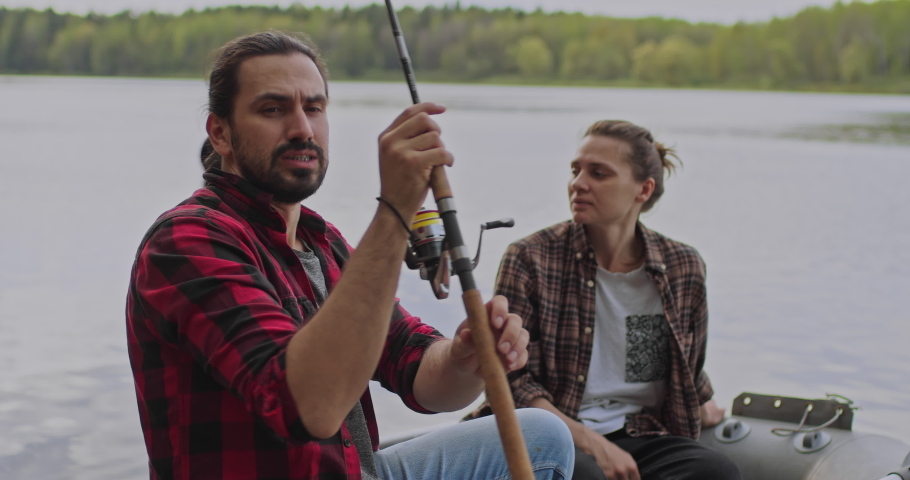 Young fishermen on an inflatable boat on the lake are fishing. Cinematic shot.