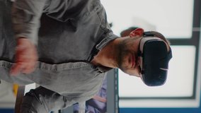 Vertical video: Video editor experiencing virtual reality headset, gesturing, editing film montage using post production software working in creative agency office. Videographer using VR goggles in