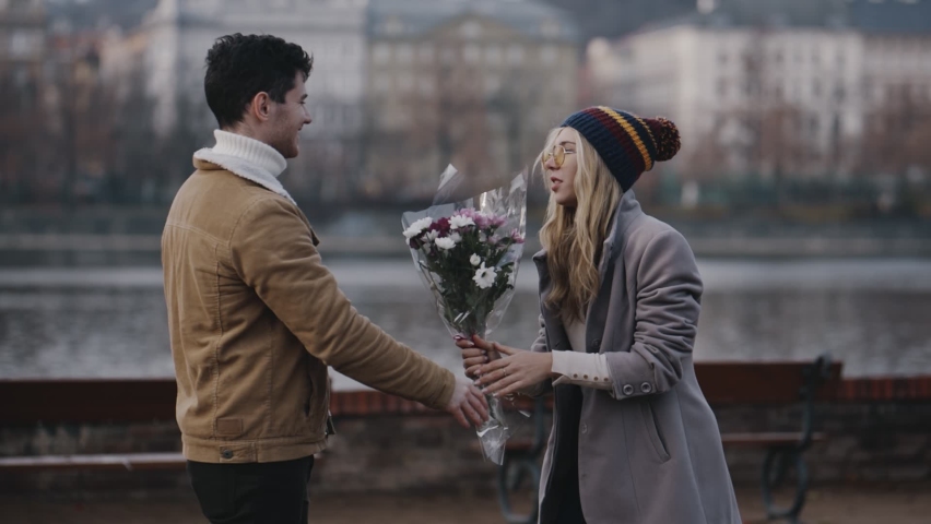 Crazy caucasian girl taking bouquet of flowers and brutally hiting guy on river embankment. Young couple screaming and quarreling on date. Jealous woman beating scared man with bouquet after betrayal. Royalty-Free Stock Footage #1076116913