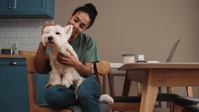 An attractive african american woman is petting the dog while sitting in the kitchen at home - Powered by Shutterstock - Get 15% off with code: PIKWIZARD15