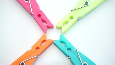 Close-up of colored plastic clothespins on a white background with rotation, top view