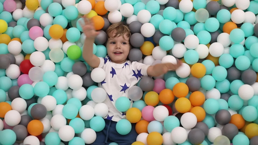 Happy playful little boy 2-3 years old in dry pool with colorful plastic balls | Shutterstock HD Video #1076127614