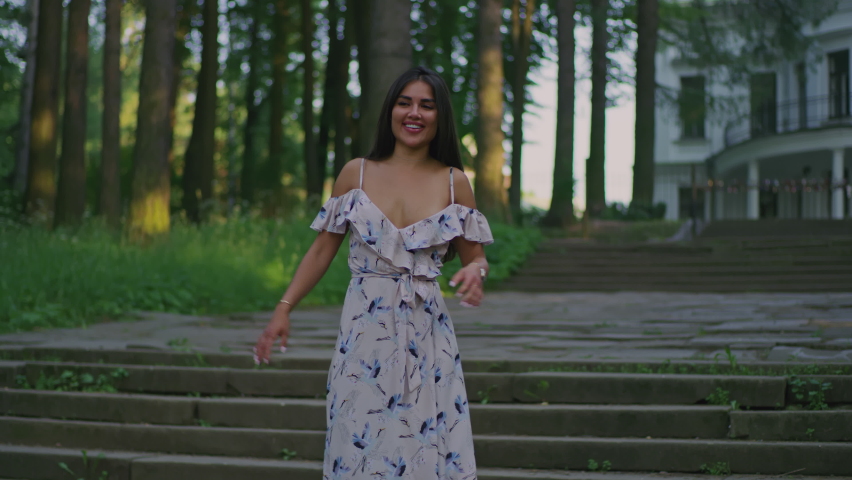 a young brunette on the background of an old manor house in a beautiful white dress