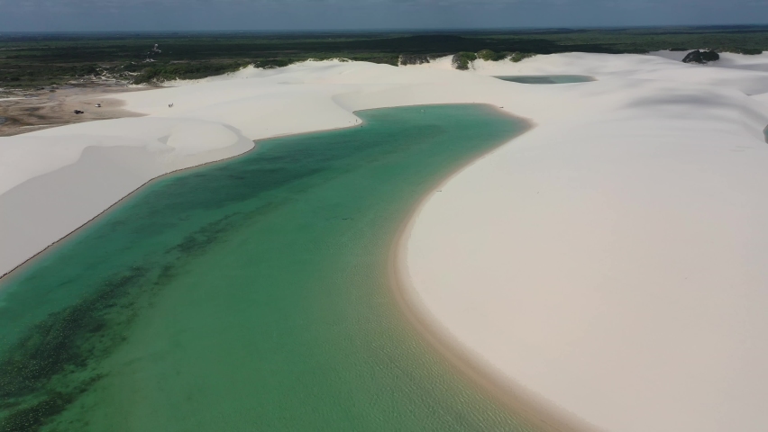 Scenic sand waves at Lençois Maranhenses National Park. Great sand dunes between rainwater lakes.  Lençois Maranhenses, Maranhao, Brazil. Paradise scenic. Scenic sand dunes aerial view.