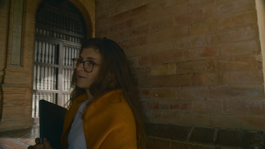 Two female students stand in university hall and discuss school project or homework assignment. Best friends chat and talk about studies in college settings. University lifestyle