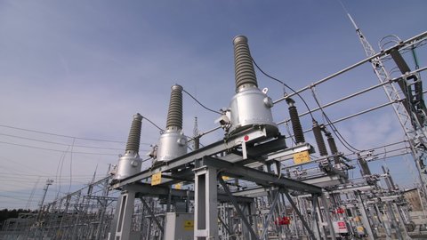 Modern equipment with ceramic insulators and cables at electricity production substation under blue sky close view