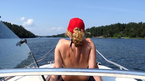 Stockholm, Sweden A woman with a red cap on a motorboat