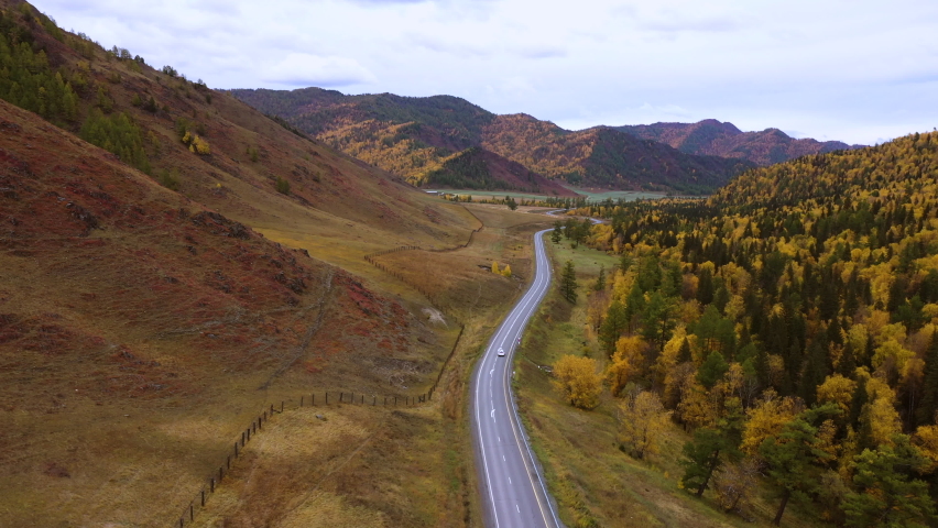 4K Aerial drone footage of small white family hatchback moving through picturesque landscape. car driving on an asphalt road with a beautiful mountainous terrain. | Shutterstock HD Video #1076145197