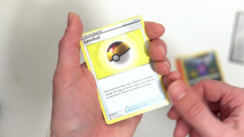 Hamburg, Germany - 07192021: male hands going through a fresh pokemon trading card booster on white background showing the cards.
