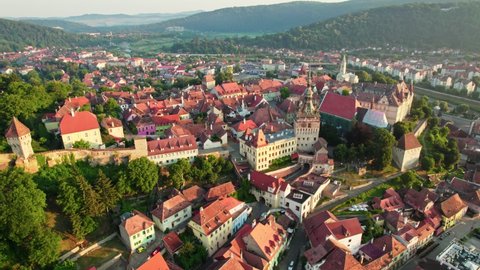 Flying around Sighisoara city center in morning lights, Romania. Aerial sunrise view of old town Sighisoara
