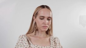 Fashion video of a beautiful elegant young woman in a pretty  beige top with a floral pattern, blue jeans posing over white background. Studio Shot. 