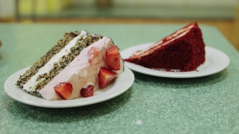 Two pieces of cake with fresh strawberries and whipped cream on a table in a cafe. Sweet and delicious dessert, close-up
