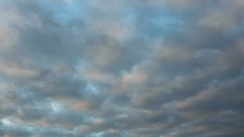 Waving patterns of small cumulus clouds into different directions with colorful sunset and dark tones of blue hour. Time lapse of weather conditions sky background.
