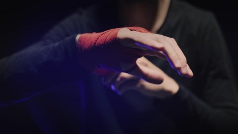 Male boxer wrapping hands before fighting in slow motion. Close-up of young athlete getting ready for fight. Man preparing. Sport concept. Close up boxer wrapping red bandages