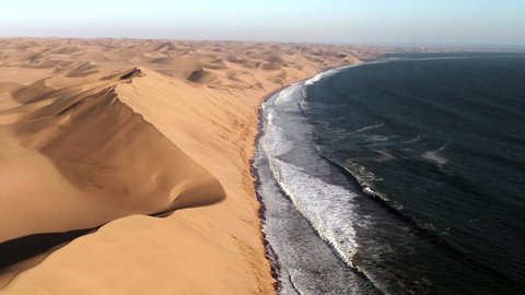 Aerial view of Sandwich Harbour, where giant sand dunes meet the Atlantic ocean, near Walvis Bay in the Namib-Naukluft National Park, Namibia.