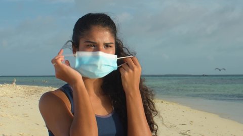 smiling latin girl take off medical mask in te tropical beach