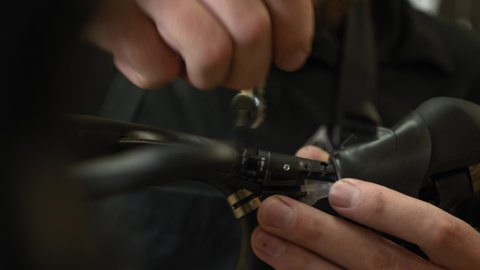 Mechanic assembles road bicycle, close up of hands. Man fixing brakes on bicycle with wrench