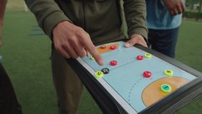 Soccer young coach explaining match tactics to group of diverse multiracial soccer players in sportswear on football pitch at daybreak. Handsome trainer instructing sportsmen to game outdoors - Powered by Shutterstock - Get 15% off with code: PIKWIZARD15