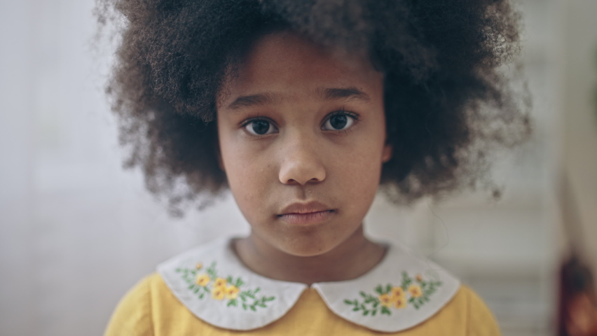 Sad lonely African-american girl with natural black hair looking into camera