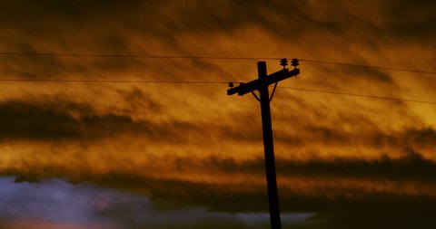 Silhouette of a common utility pole against the brilliantly saturated reds of clearing storm clouds during the final moments of a mid-summers sunset.  2 fps. 