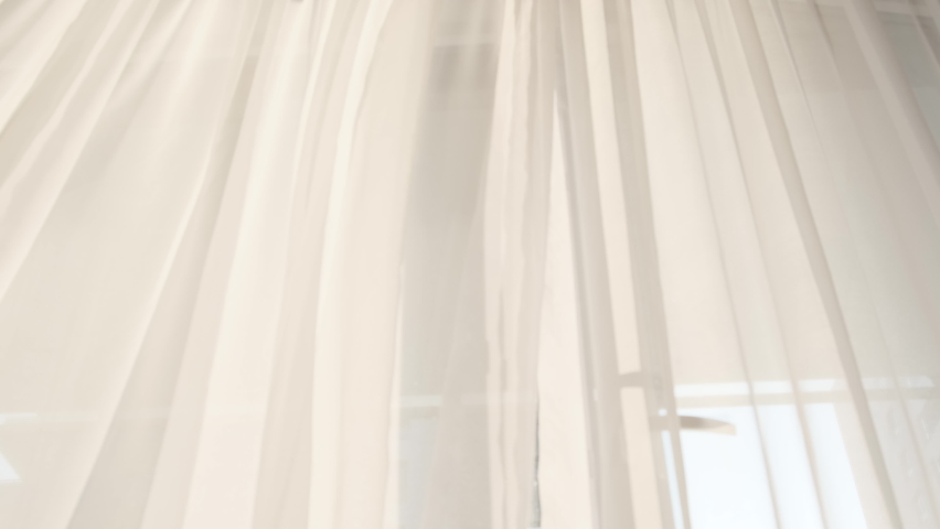 Transparent white curtain tulle moves from the wind from an open window. Sunny day, the sun's rays sunlight. Royalty-Free Stock Footage #1076178551